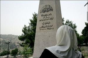 Женщина читает молитву на мемориале, воздвигнутом в честь защитников Палестины.