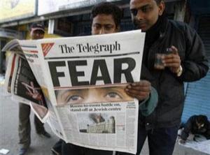 Жители Мумбаи читают репортаж в газете The Telegraph с места трагедии