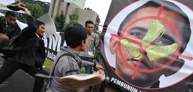 Протестующие в Индонезии кидают ботинки в плакат с изображением Барака Обамы