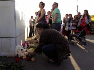Люди несут цветы и игрушки на берег неподалеку от места трагедии