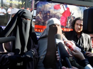 Кенза Драйдер (в центре) дает интервью журналистам на фоне своего рекламного автобуса