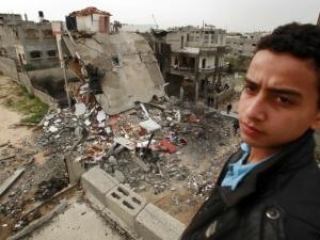 Палестинский юноша стоит возле дома, разрушенного в результате израильской бомбардировки в г.Джабалия на севере сектора Газа