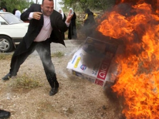 Палестинец бросает в огонь продукцию, изготовленную в незаконном еврейском поселении