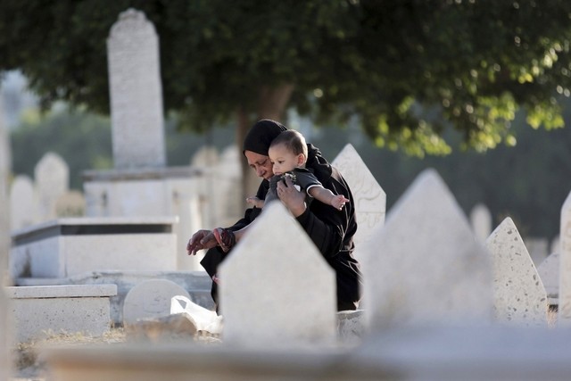 Жительница Газы с ребенком навещает могилу родственника