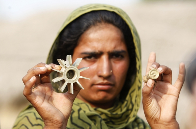 Жительница Кашмира демонстрирует детали от минометного снаряда, выпущенного со стороны Пакистана