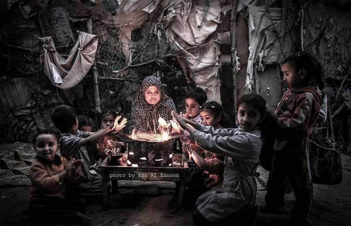 Женщина и дети в Газе греются около горелки