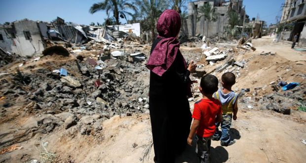 Жительница сектора Газа с детьми на фоне руин домов, разрушенных в результате израильских бомбардировок