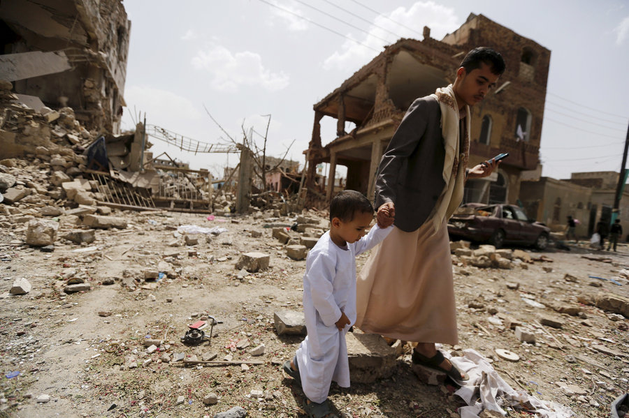Мужчина идет с мальчиком по улице, разрушенной в результате бомбардировок