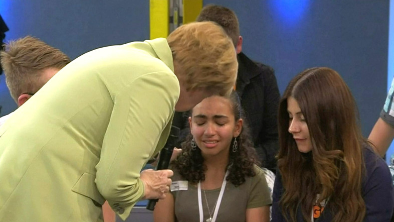 Меркель неуклюже утешает школьницу