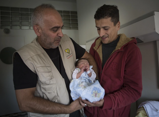 Родившийся на чужбине малыш со своим отцом и венгерским волонтером