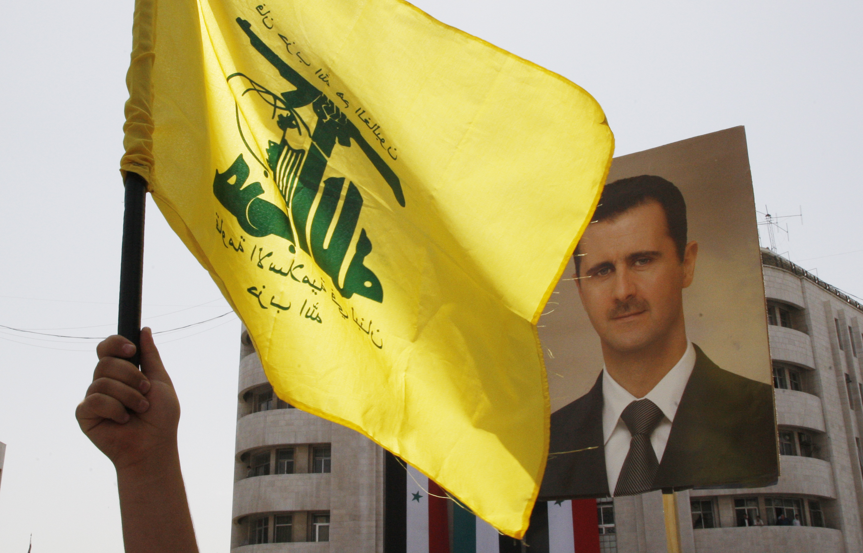 Флаг Хезболлы в Дамаске на фоне портрета президента Асада