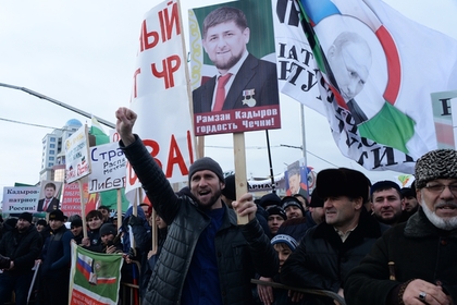 Участники митинга в Грозном держат плакаты с изображением Путина и Кадырова