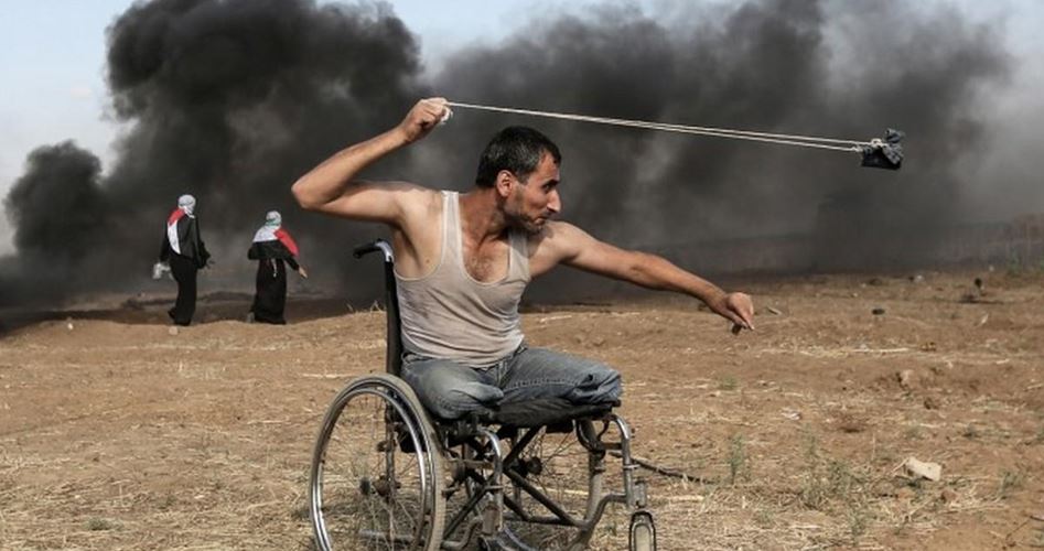 Житель Газы Сабер аль-Ашкар метает камни в израильских силовиков