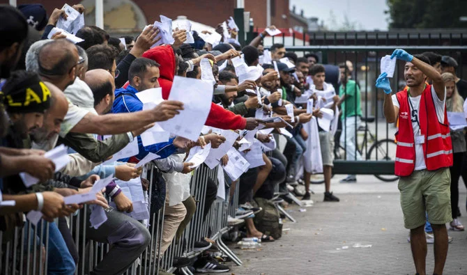 Соискатели убежища в Тер Апеле показывают документы, чтобы получить место в миграционном центре