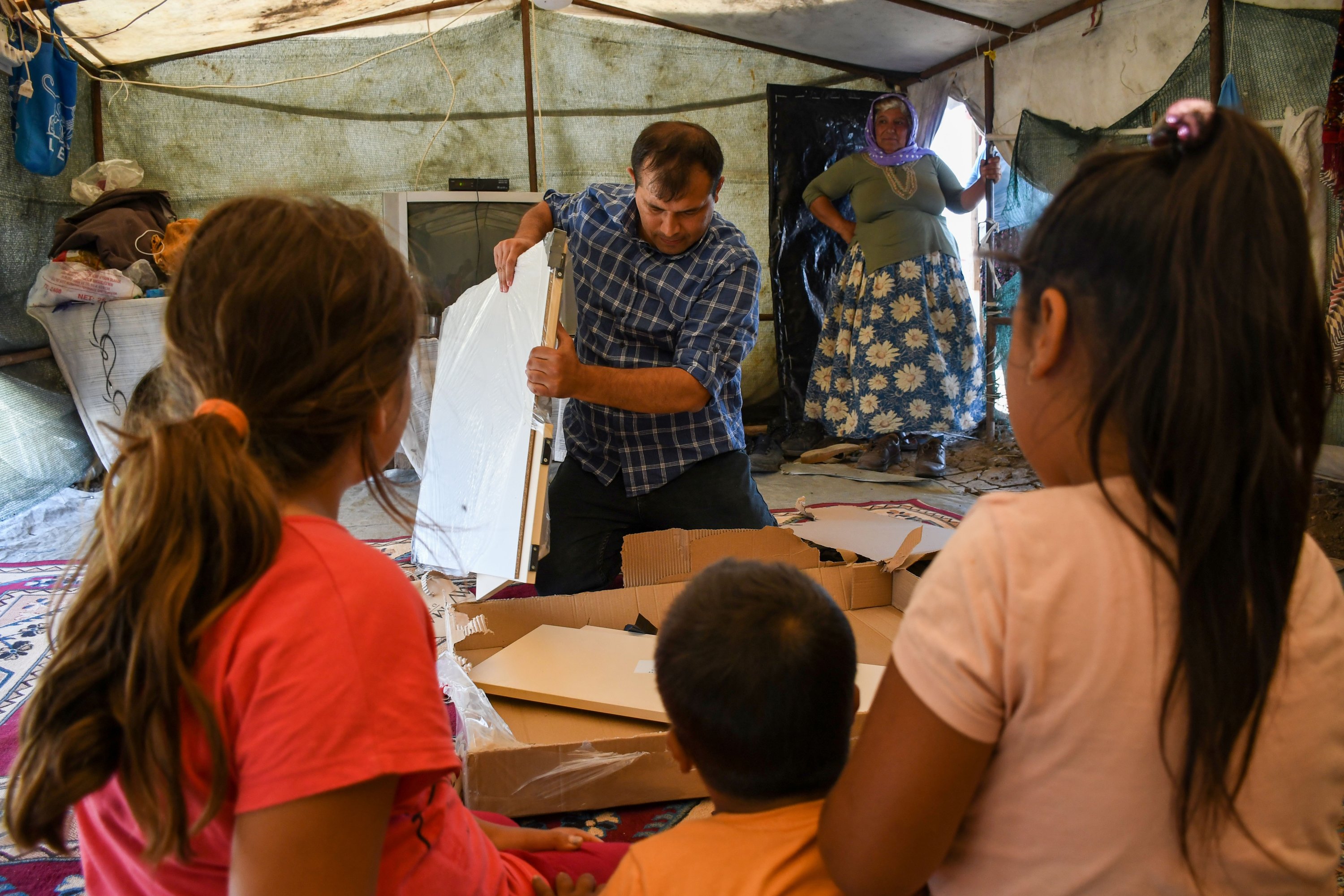 Ахмет Ерликайя монтирует книжный шкаф в лагере сезонных рабочих в провинции Адана
